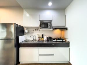 a kitchen with white cabinets and a stainless steel refrigerator at Downtown Stay 65 sqm - Ultra-WiFi - BTS Ratchathewi in Pom Prap