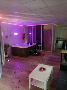 a room with a tub with purple lights and a table at CocoonSpa Love Room Jacuzzi Privatif in Toulouse +8 photos