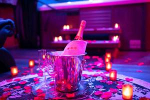 a bottle of wine in a bucket on a table with candles at CocoonSpa Love Room Jacuzzi Privatif in Toulouse