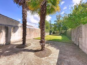 dos palmeras de pie junto a una pared en Holiday Home Les Vents Doux by Interhome, en Tharon-Plage