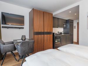 a hotel room with two beds and a desk and a kitchen at Studio Studio Taxacher by Interhome in Krinberg +21 photos