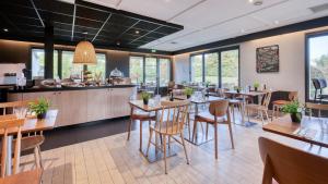 a restaurant with tables and chairs and a counter at Campanile NATURE - Bordeaux Sud Gradignan Talence in Gradignan