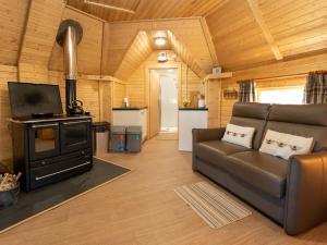 a living room with a couch and a stove at Chalet Birch Bothy by Interhome in Coldstone
