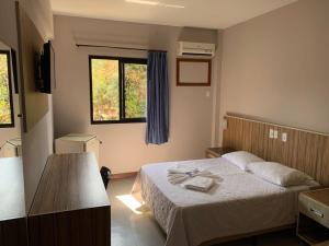 a bedroom with a bed with a table with towels on it at Hotel Rinkao in Cachoeiro de Itapemirim