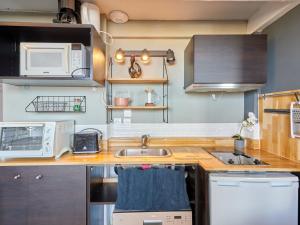 a kitchen with a sink and a microwave at Apartment Le Nid de Juno Beach by Interhome in Courseulles-sur-Mer +6 photos
