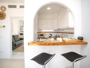a kitchen with white cabinets and a counter with two stools at Apartment Imperial Park-23 by Interhome in Casas de Torrat