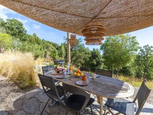 a wooden table with chairs under a straw umbrella at Holiday Home Casa Murato by Interhome in San-Giuliano