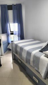 a bedroom with a bed and a window with blue curtains at El Pommier in Fisterra
