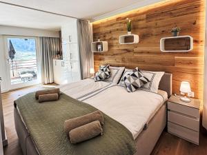 een slaapkamer met een groot bed met een houten wand bij Apartment Ringstrasse - Utoring-64 by Interhome in Leukerbad