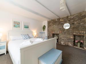 a bedroom with a white bed and a stone wall at Holiday Home Mermaid Cottage by Interhome in Mevagissey