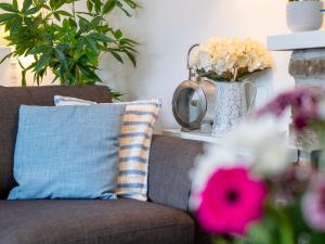 a couch with a pillow and a vase of flowers at Holiday Home Mermaid Cottage by Interhome in Mevagissey