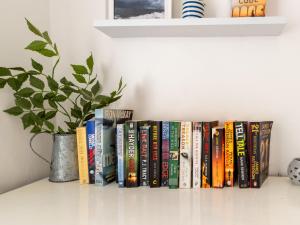 a row of books on a shelf with a plant at Holiday Home Mermaid Cottage by Interhome in Mevagissey +43 photos