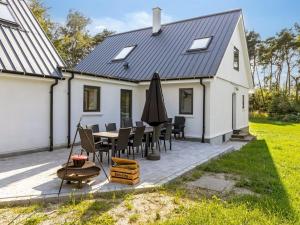 a white house with a table and chairs and an umbrella at Holiday Home Wolter - 1-7km from the sea by Interhome in Vesterø Havn