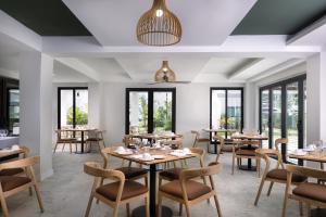 ein Restaurant mit Tischen und Stühlen und Fenstern in der Unterkunft Negril Footeprints Hotel in Negril
