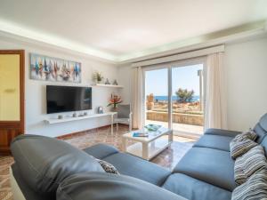 ein Wohnzimmer mit einem blauen Sofa und einem Fernseher in der Unterkunft Holiday Home Villa Can Rosito by Interhome in S'Illot