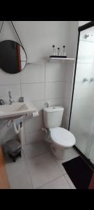 a white bathroom with a toilet and a sink at Apartamento garden in Resende
