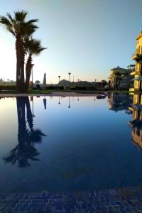 einem Wasserpool mit einer Palme und einem Gebäude in der Unterkunft Appart Residence Haut Standing in Bouznika + 3 Fotos