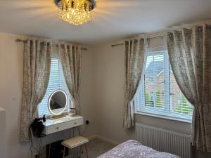 1 dormitorio con espejo, cama y lámpara de araña en ADI Holiday Home Lurgan, en Lurgan