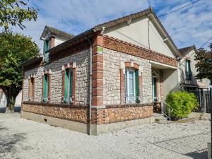 a brick house with green windows on a street at Le temps d'une pause -1- in Cepoy