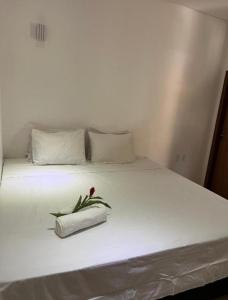 a white bed with a flower on top of it at Casa Lalivi Trancoso in Porto Seguro