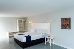 a bedroom with a large white bed and a table at Ancora Boutique Hotel in Vilanculos