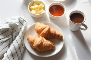 a table with a plate of croissants and a cup of coffee at Mustard Hostel in Dijon