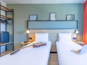 two beds in a room with a laptop on it at Hotel ibis Guimaraes in Guimarães