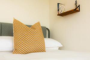 a bed with yellow and white pillows on it at Oaklane Glamping Cabins in Kenmare