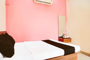 une chambre avec un lit blanc et un mur rose dans l'établissement Hotel O Samruddhi Executive Lodge, à Pune