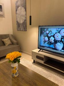 a living room with a television and a vase of flowers at غرفتين وصاله هادئه in Quai