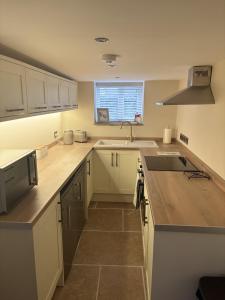 eine Küche mit weißen Schränken und einer Spüle und einem Fenster in der Unterkunft Sunset Cottage - 55 South Lane in Holmfirth + 19 Fotos