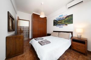 una camera con letto bianco e cassettiera in legno di Casa Linda a Olhão