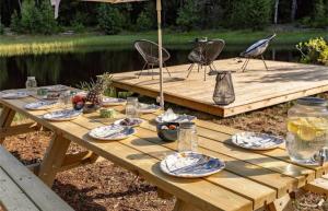a wooden picnic table with plates of food and an umbrella at Villa Orreforshult in Orrefors