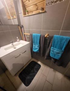 a bathroom with a white sink and blue towels at Grand studio Anse à l'Âne face a la plage et commerces in Les Trois-Îlets