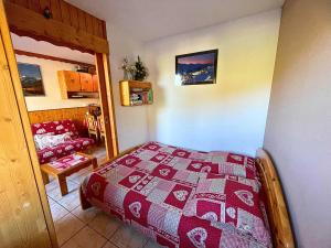 ein Schlafzimmer mit einem Bett mit einer roten Decke in der Unterkunft Grand studio pour 4, Les Menuires, aux pieds des pistes - FR-1-452-397 in Les Menuires