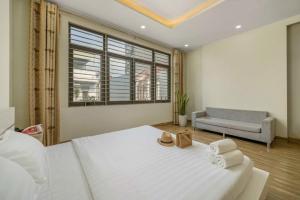 a bedroom with a large white bed and a couch at Anh House 85 in Da Nang