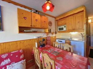 eine Küche mit einem Tisch und einem roten Tischtuch in der Unterkunft Grand studio pour 4, Les Menuires, aux pieds des pistes - FR-1-452-397 in Les Menuires
