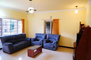 un salon avec un canapé bleu et une chaise dans l'établissement KP Holidays తెలుగు Cottage, à Ooty