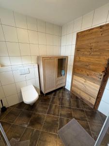 a bathroom with a toilet and a wooden door at Ferienwohnung Prutz Tullenweg 17 Oberinntal Tirol in Prutz