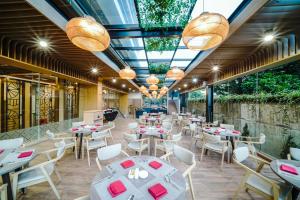a restaurant with white tables and chairs and chandeliers at Truntum Cihampelas in Bandung