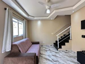 een woonkamer met een bank en een plafondventilator bij Estadia no Caiçara com Praia a 150m! in Vila Balneária