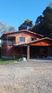a wooden house with a porch and a driveway at Casa rústica às margens do lago in Maximiliano de Almeida +12 photos