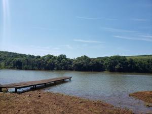 a dock in the middle of a body of water at Casa rústica às margens do lago in Maximiliano de Almeida