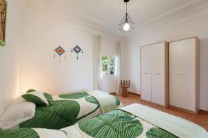 zwei Betten in einem weißen Zimmer mit grünen und weißen in der Unterkunft Finca Pisaverde, a peaceful haven between the sea and Teide in El Pris