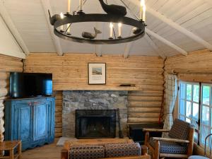 a living room with a stone fireplace and a chandelier at Au Pic de l'Aurore Motel-Chalets in Perce