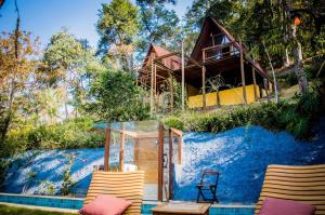 a house on a hill with two chairs and a pool at Chalé Águia in Petrópolis