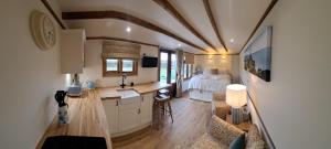 a room with a kitchen and a bedroom with a bed at Ty Beti at Gorlan yr Efail Shepherds Hut with Private Hot Tub in Holyhead
