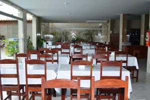 a dining room with white tables and wooden chairs at Solar Hotel in São Fidélis