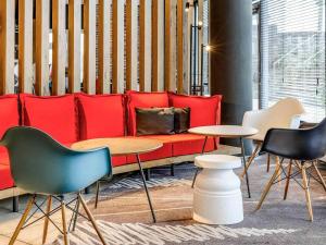a room with a red couch and chairs and tables at ibis Hotel Würzburg City in Würzburg