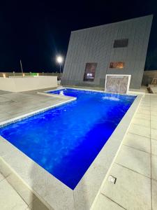 a blue swimming pool in front of a building at night at Chalé da Serra in Araruna